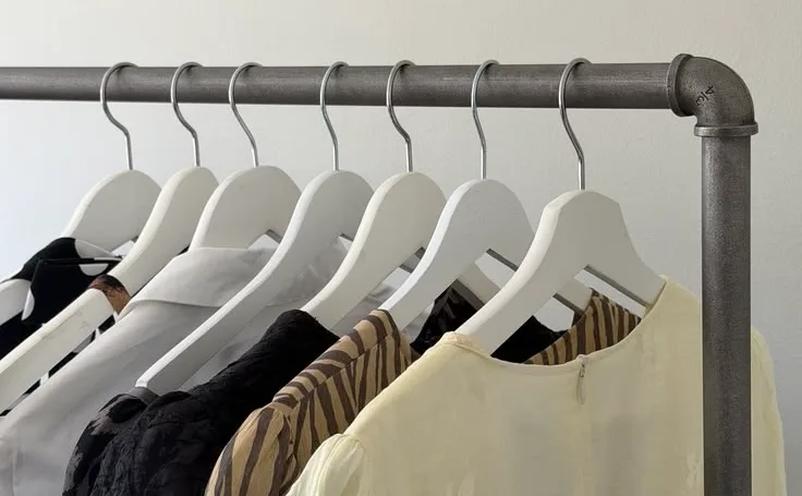 A row of white hangers on a steel rail in a store